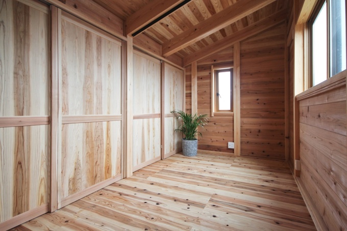 簡素な木材のデザインが施された小屋裏収納。日常的な使い勝手を重視した造りで、片付けが簡単。植物がアクセントとして配置されている。