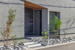 静かに迎え入れるシンプルでモダンな玄関。天然石が周囲を彩り、落ち着いた雰囲気を醸し出している。【チェックハウス】
