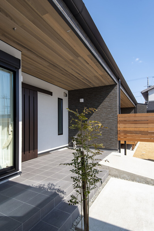 ナチュラルな色合いの外壁と天井で構成された住宅の外観。周囲には木々が植えられ、自然と調和したデザインが魅力的である。