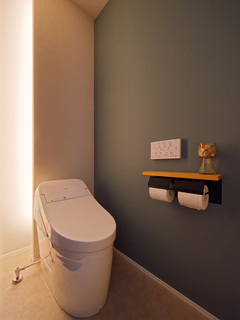 トイレの奥をふかし、間接照明をいれつつ、収納スペースを作る考え抜かれたトイレ。ダウンライトを使わず、暗めなクロスと間接照明で落ち着きのある空間に。