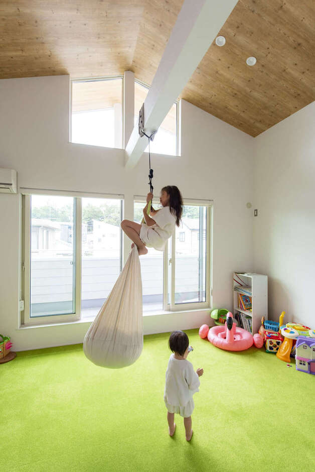 勾配天井の子ども部屋は10畳。成長に応じて間仕切りもできる。太い梁にハンモックを吊るしてアスレチック気分を満喫。部屋全体を明るくするために黄緑色のカーペットや木目天井などデザイン性にもこだわり、のびのびと楽しく遊べる空間を実現した