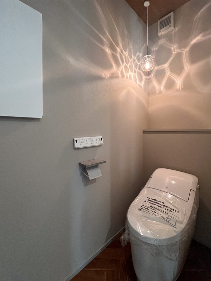 グレーのアクセントクロスを採用した落ち着きのある空間。モノトーンでホテルライク、おしゃれなトイレに仕上がりました。