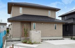 落ち着いた色調の2階建て住宅の外観。モダンなデザインで、周囲の景観に調和しつつも存在感を放っている。