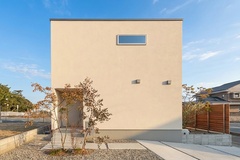シンプルなデザインが印象的な住宅の外観。上部に取り付けられた横長の窓がモダンな雰囲気を添えており、洗練された印象を与える。