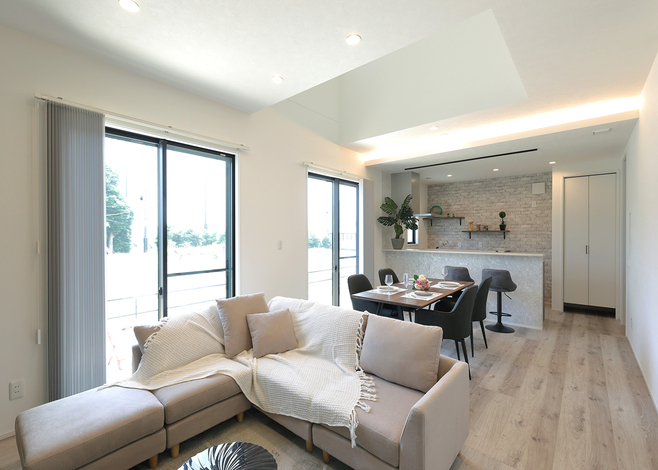 吹き抜けの高窓から光が降り注ぐ、開放的なLDK。グレーでまとまった室内と間接照明がホテルのような雰囲気を出している