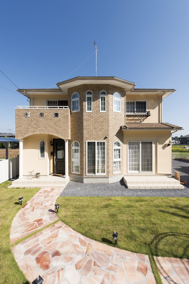 洗練されたデザインが特徴の二階建て住宅。大きな窓とバルコニーがアクセントとなり、明るく開放的な表情を持つ外観。