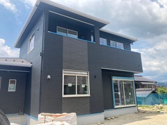 モダンなデザインの二階建て住宅。落ち着いた色合いの外壁と大きな窓が印象的で、周囲の環境に調和している。【フラット】