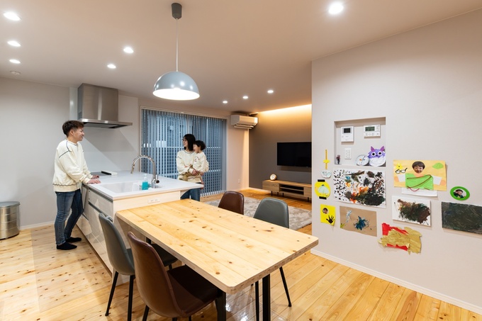檜の床材を使ったダイニングテーブルはご主人がDIYしたもの。ダイニング側の壁は、お子様の作品の展示コーナーに。