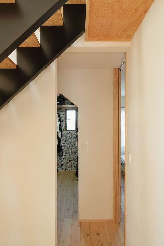 奥まった場所に設けた寝室の入口は、天井まで届くハイサイズの引き戸に。階段下に開放感をもたらす。クローゼットも三角の入口にてパントリーと揃えた