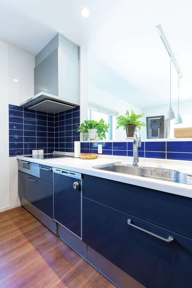 親世帯のキッチン。タイルとキッチンパネルの鮮やかなブルーがポイントになっている。お母さまの大好きな山の景色を見ながら料理できるよう、窓の大きさと位置を工夫した