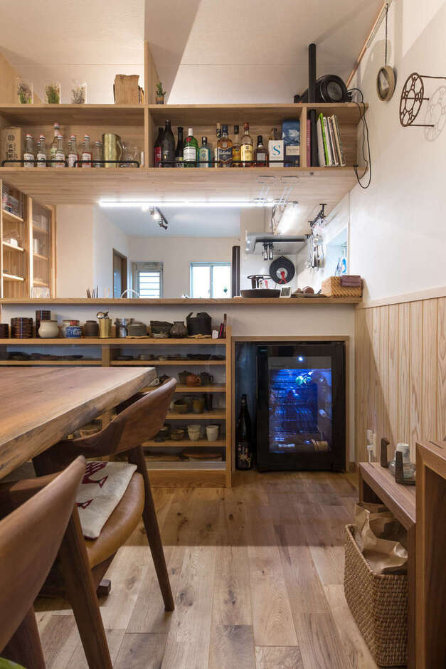 キッチンの壁面を利用してダイニング側には豊富な茶器を収納するカップボードを造作。隣にはワインセラーを設けた。吊り収納はインテリア性も高いお酒のボトルをディスプレイ