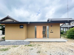 木の温もりが感じられるシンプルな平屋の外観。落ち着いた色合いが周囲の風景と調和し、穏やかな住宅環境を感じさせるデザイン。【明城】