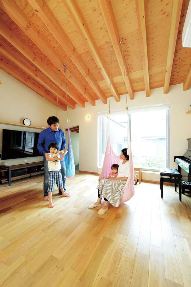 床にも天井にも無垢材を使用した子世帯のLDK。配線を隠せるTVボードを造作し、空間をすっきりと見せる。中庭の景色もリビングの一部として楽しめる