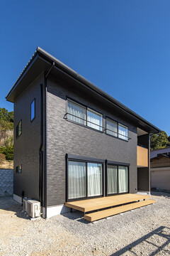 黒い外壁が特徴的な２階建て住宅。広い庭と木製デッキがリラックスできる空間を提供している【トキワハウス デザイン アンド ビルド（常盤工業）】