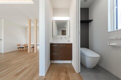 モダンなデザインのトイレ空間。シンプルな内装が清潔感を演出し、木目調のキャビネットがアクセントを加えている。【PG HOUSE（ピージーハウス）浜松・磐田】